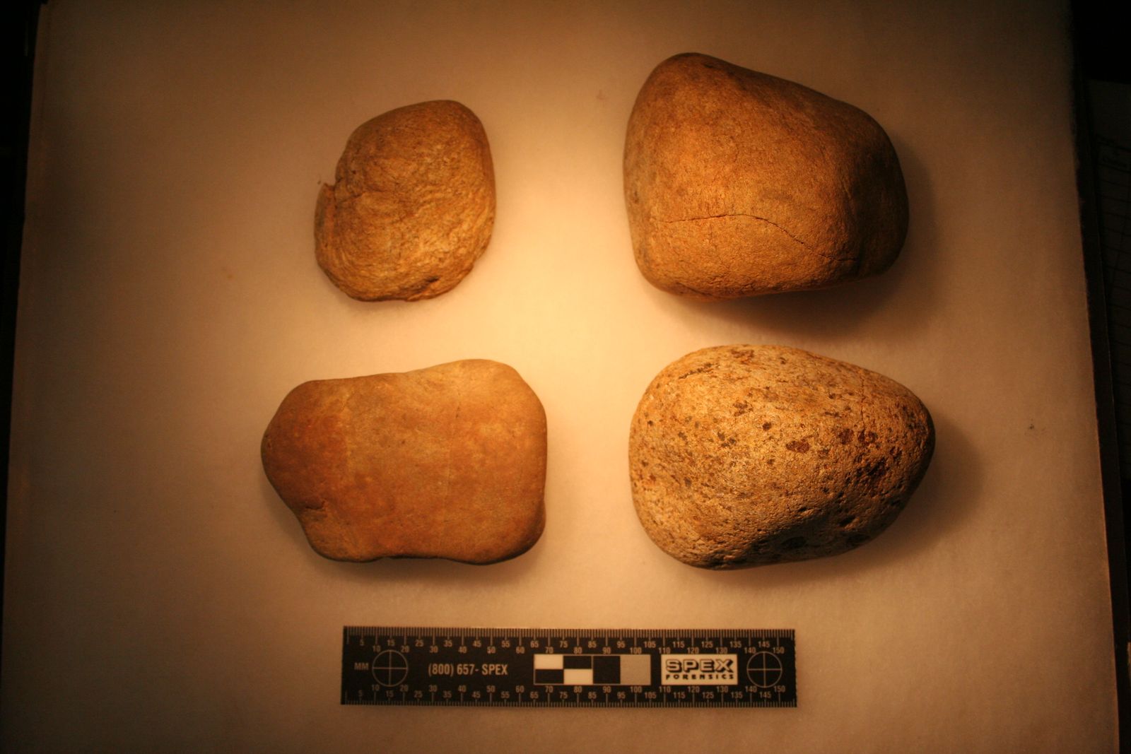 Four stone cobble tools on a dark background